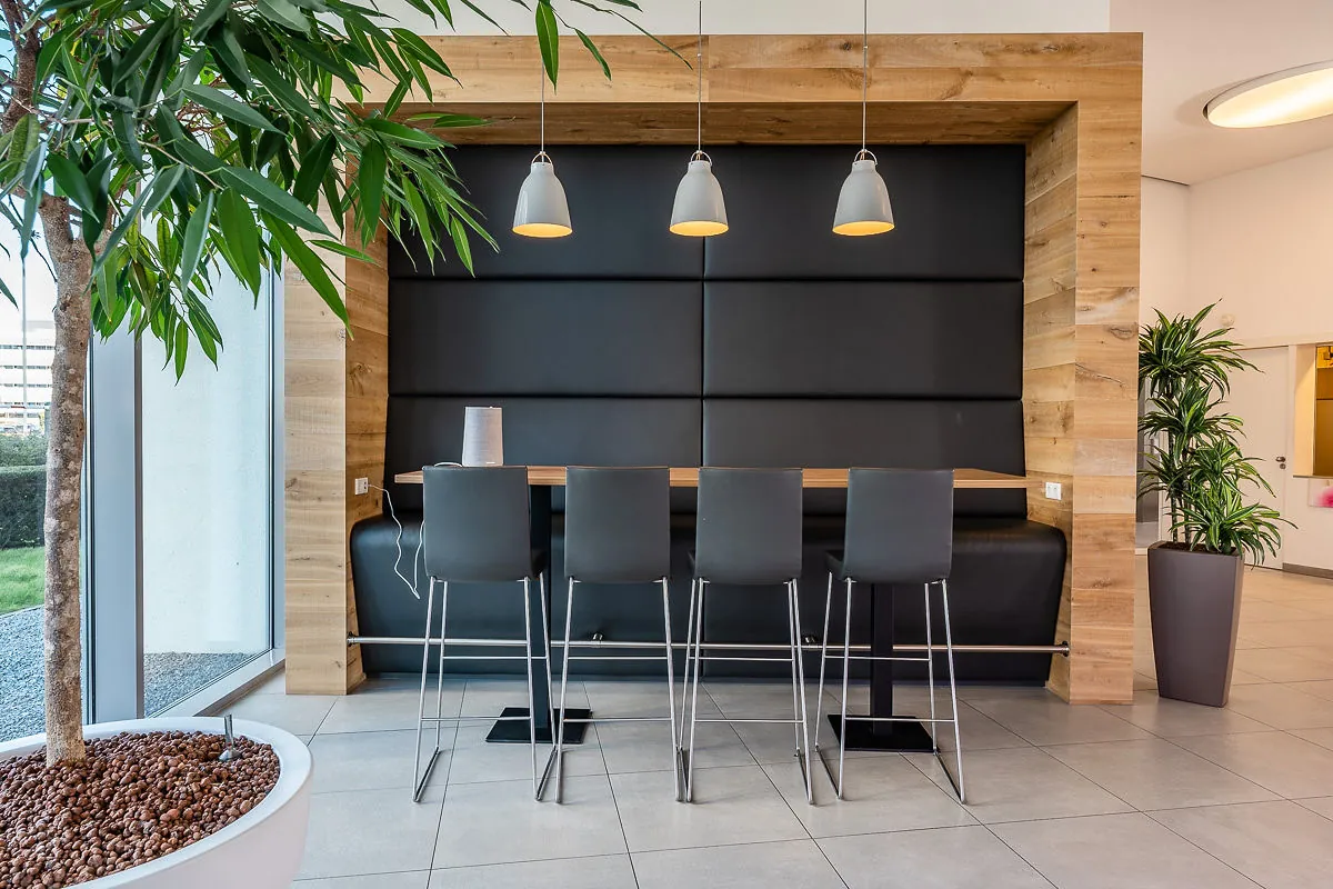 Moderne zithoek met hoge stoelen en houten omlijsting in een kantoorruimte aan het Rivium Quadrant.